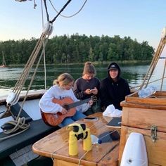 three people sitting on a boat playing guitars