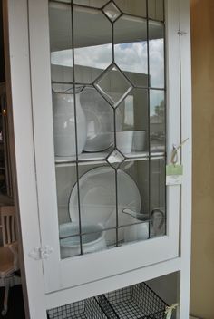 a white china cabinet sitting next to a window with glass doors and shelves on each side