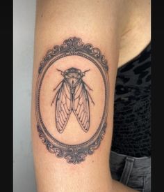 a black and white photo of a moth in a frame tattoo on the right arm