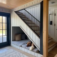 a dog is laying down on the bed under the stairs in this house with its head resting on the pillow