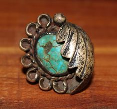 This ring in found condition shows its history and life in the patina and wear. North the cracked and chipped stone, most likely turquoise, and the dirt and patina of the metal, most likely silver. The ring features an oval cabochon green stone framed with a partial circle of small horseshoes and a feather partially folded over one half of the stone. The ring is unmarked and the materials are assumed to be turquoise and silver, but this is not guaranteed. Likewise, the ring is culturally attribu Antique Silver Turquoise Ring With Patina, Rustic Silver Jewelry With Patina, Vintage Adjustable Engraved Turquoise Ring, Rustic Silver Rings With Patina, Antique Turquoise Ring With Patina, Vintage Turquoise Concho Ring, Vintage Concho Ring Jewelry, Vintage Turquoise Ring With Patina, Jewelry Turquoise