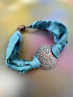 Handmade bohemian-style bracelet featuring upcycled teal sari silk, a copper plated compass charm with verdigris patina, and a magnetic clasp.  - Approximately 7 inches. (Need a different size? Include a "Note to Seller" during checkout and we'll make it fit--free of charge!) - Easy-on/easy-off magnetic clasp closure.  -------------------- The textile fabric used to make this bracelet is upcycled from torn and dyed silk that was leftover from the sari manufacturing process. These bracelets look Sari Silk Jewelry, Silk Wrap Bracelets, Diy Jewellery Designs, Fiber Art Jewelry, Silk Bracelet, Silk Jewelry, Artisan Jewelry Handmade, Dyed Silk, Sari Silk