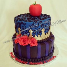 a birthday cake with an apple on top and flowers around the edges is decorated in blue, purple, and red