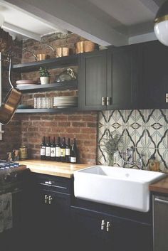 a kitchen with black cabinets, white sink and wooden counter tops in front of a brick wall