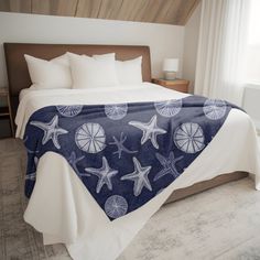 a bed with a blue and white bedspread that has starfish on it