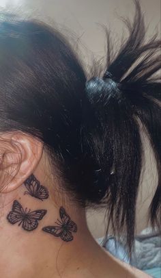 the back of a woman's neck with butterfly tattoos on her left side ear