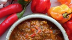 a white bowl filled with chili next to red peppers