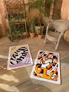 two rugs with designs on them sitting next to a chair and potted plant