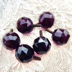 four dark purple glass beads are sitting on a lace doily