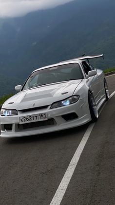 a white car driving down the road with mountains in the background