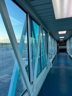 an airport walkway with windows and railings leading to the tarmac at dusk or dawn