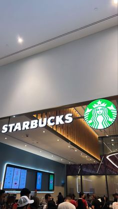 people are standing in line at starbucks's coffee shop with the starbucks logo above it