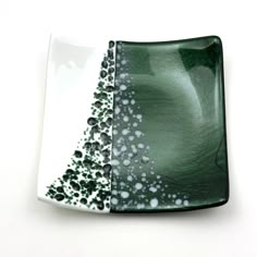 a green and white plate with some black dots on it's side, sitting on a table