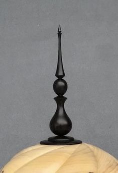 a black candle holder sitting on top of a wooden table next to a gray wall