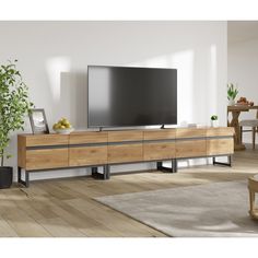 a flat screen tv sitting on top of a wooden entertainment center in a living room