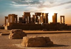 the sun is setting behind some ancient ruins in the middle of the desert with large rocks