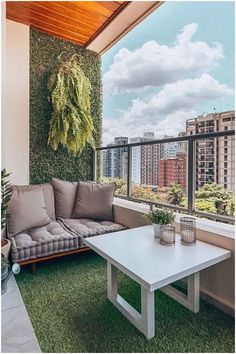 a couch and coffee table on a balcony with green grass in front of the windows