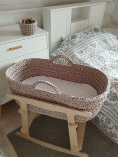 a crocheted bassinet sits on a wooden stand next to a bed