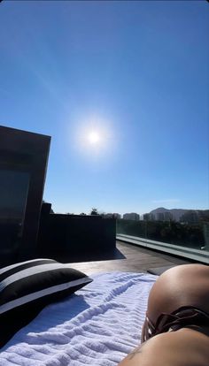 a woman laying on top of a white towel next to a laptop computer and pillow