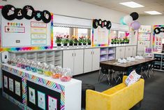 an empty classroom with tables, chairs and decorations on the wall in front of them