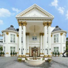 a large white building with columns and pillars on the front entrance, surrounded by greenery