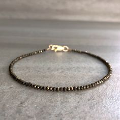 This natural gemstone bracelet features tiny Pyrite crystals. The small glittering beads are a neutral metallic hue. This is a unique, but versatile piece that is perfect alone or layered. These crystals are teeny tiny, about 2 mm each. If you love the look of delicate, dainty jewelry, this bracelet is perfect for you. At checkout, choose a sterling silver or 14K gold filled clasp for your bracelet. * METAPHYSICAL PROPERITIES OF PYRITE * confidence creativity grounding motivation prosperity vita Minimalist Faceted Beads Rondelle Bracelets, Minimalist Rondelle Bracelets With Faceted Beads, Minimalist Bracelets With Faceted Rondelle Beads, Minimalist Round Bracelet With Faceted Beads, Minimalist Rondelle Gemstone Beads Bracelets, Tiny Bead Bracelet, Pyrite Jewelry, Pyrite Bracelet, Intention Bracelets