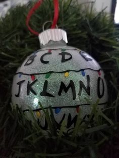 a glass ornament with the word klimo written on it is hanging from a christmas tree