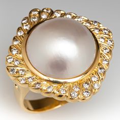 This fabulous vintage cocktail ring is centered with one (1), bezel set, round maybe' pearl and is bordered with thirty-six (36), bead set, round brilliant cut diamond. The ring measures 24.9mm at the top, rises 11.0mm above the finger, tapering to 3.4mm wide and 1.1mm thick at the base of the shank. The ring is currently size 6.5. Vintage Gold And Platinum Cocktail Rings, Luxury Antique Pearl Ring With Diamond, Luxury Antique Style Cabochon Pearl Ring, Luxury Classic Pearl Ring With Rose Cut Diamonds, Luxury Yellow Gold Brilliant Cut Pearl Ring, Classic Diamond Cabochon Ring, Classic Diamond Ring With Cabochon Cut, Formal Cabochon Diamond Ring, Formal Round Cabochon Diamond Ring