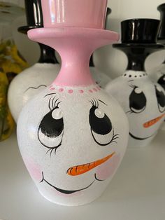 three vases with faces painted on them sitting on a table next to each other