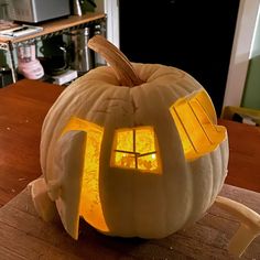 a pumpkin shaped like a house with windows on it's face and lights inside