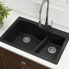 a kitchen sink with two faucets on the side and a potted plant next to it