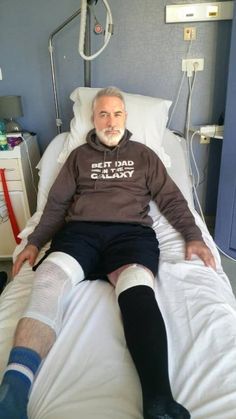 an older man laying in a hospital bed with his leg wrapped around him and socks on