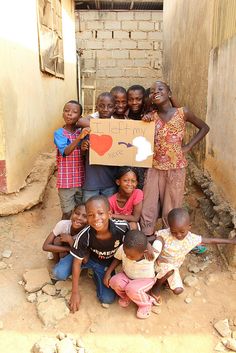 a group of children standing around each other holding a sign