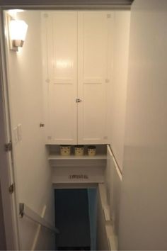 an empty room with white cupboards and blue carpeted stairs leading up to the door