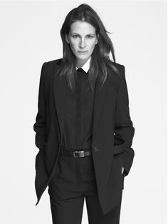 a woman in a suit and tie poses for the camera with her hands on her hips