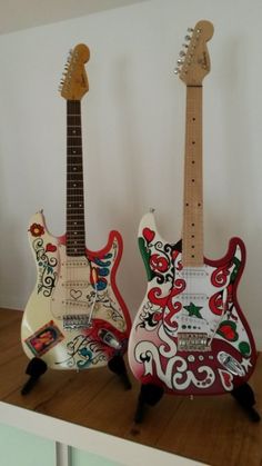 two guitars are sitting side by side on a shelf