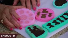 a woman's hands on top of a cake with icing and chocolate decorations