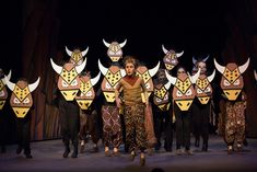 a group of people standing on top of a stage with masks around their heads and body