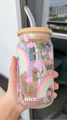 a person holding a glass jar with hearts and rainbows painted on it