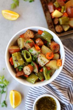 a white bowl filled with vegetables next to some lemons