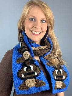 a woman wearing a blue and brown knitted scarf with an ornament on it