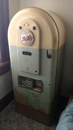 an old soda machine sitting next to a window in a room with carpeted flooring