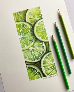 two pencils are next to a drawing of lime slices