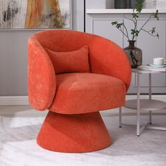 an orange chair sitting on top of a white rug next to a table and potted plant