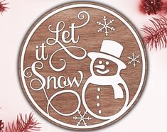 a wooden sign that says let it snow with a snowman in the center and pine branches