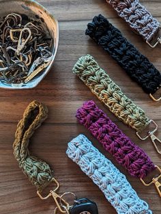 several crocheted key chains on a wooden table next to a bowl of keys