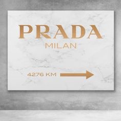 a white marble sign with gold lettering and an arrow pointing to the word prada