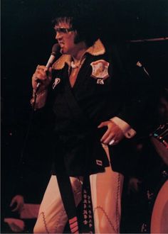 elvis presley singing into a microphone at a concert