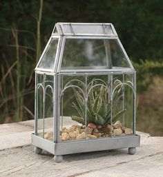 a small glass and metal planter on top of a wooden table with plants in it