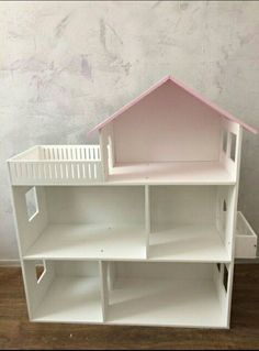 a doll house with white shelves and pink roof